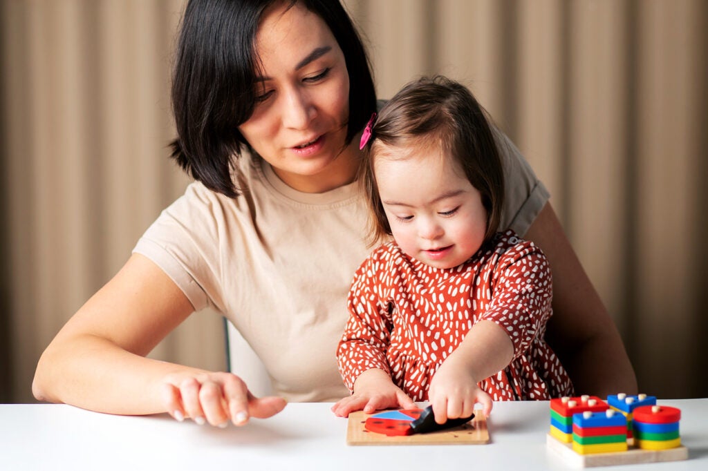 A mother plays with her baby who has Down Syndrome