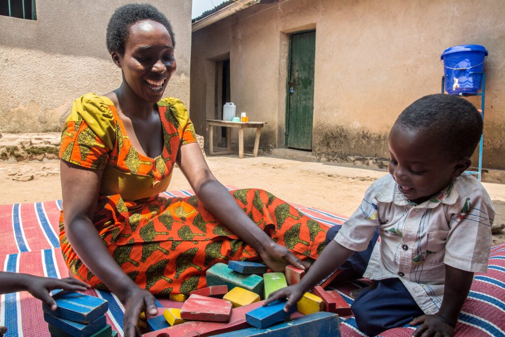 A woman watches a young boy play with blocks in Ghana