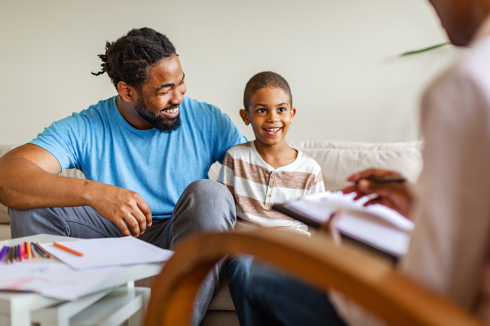A Black child and his father speak to a person who is just out of frame