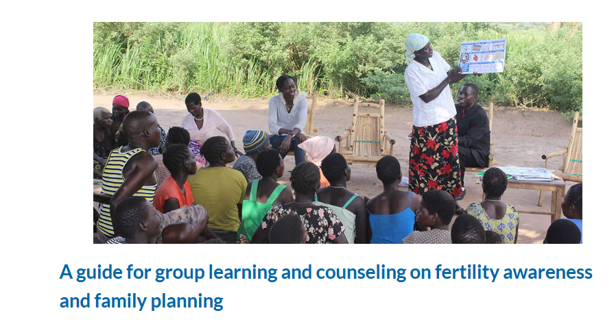 A community health education session taking place outdoors in what appears to be a rural African setting. A healthcare worker or educator in a white shirt and patterned skirt stands addressing a seated group of approximately 20-25 community members, including women, men, and children. The participants are sitting on the ground in a semi-circle, wearing colorful clothing in various patterns and bright colors including yellow, green, blue, and red. The educator is holding up what appears to be an educational poster or chart. The setting is outdoors with lush green vegetation and trees in the background, and the ground appears to be packed earth. Small wooden stools are visible in the scene. The image accompanies a guide about group learning and counseling on fertility awareness and family planning.
